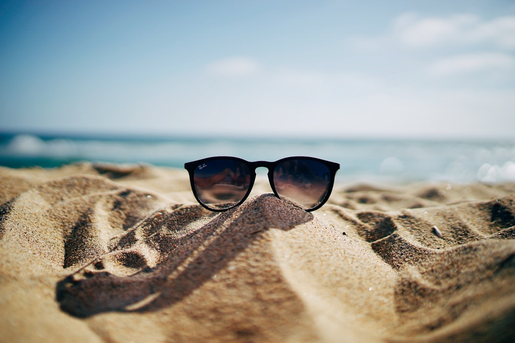 Sunglasses on a pile of sand at the beach.