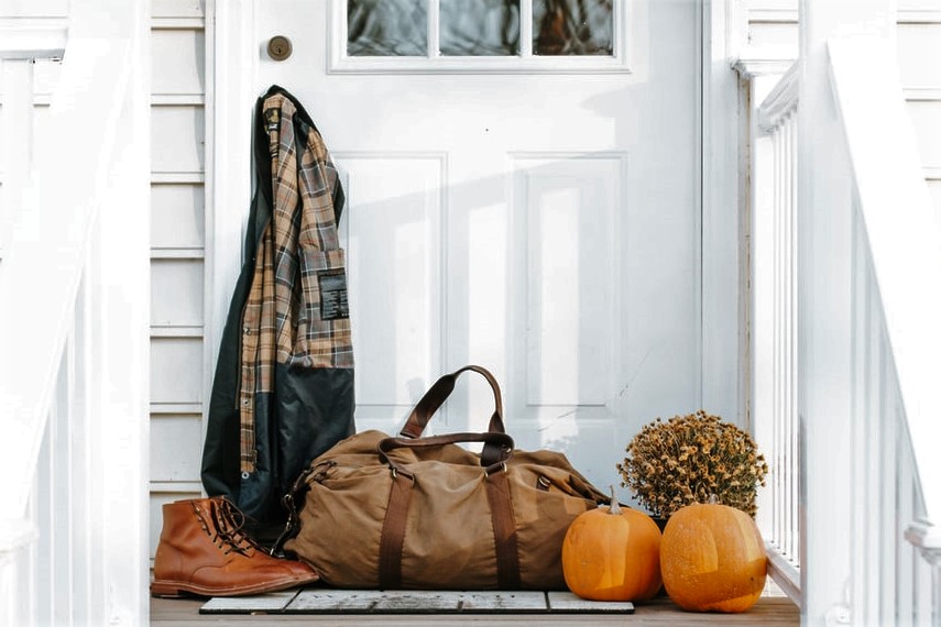 Pumpkins, duffel bag and coat hanging on farmhouse door